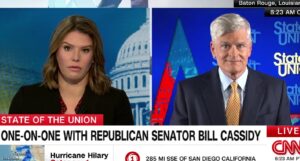 A cable news split screen on CNN showing a light-skinned woman on the left and an older light-skinned man on the right